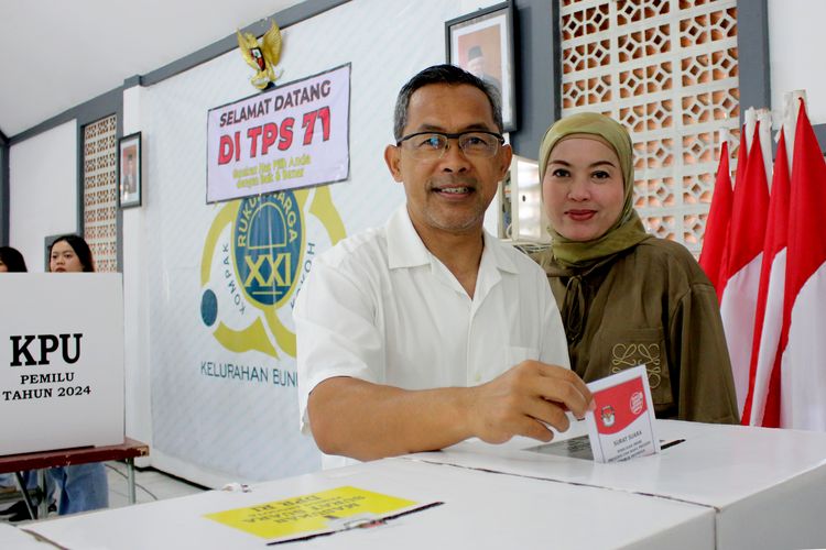 Pelatih Persikabo 1973 Aji Santoso dan istri saat memasukkan surat suara sesudah melaksanakan pencoblosan untuk Pemilu 2024 di Balai RW tempat tinggalnya di Malang, Jawa Timur, Rabu (14/2/2024) siang. 