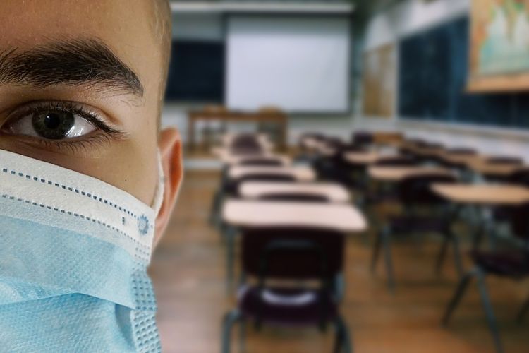 A masked student in his classroom 