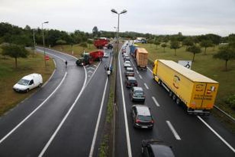 Para petani Perancis menggunakan mobil-mobil pertanian dan truk untuk memblokir sebuah ruas jalan yang menuju ke kota Caen, Senin (20/7/2015). Aksi ini adalah bagian dari unjuk rasa menuntut kenaikan harga susu dan daging.