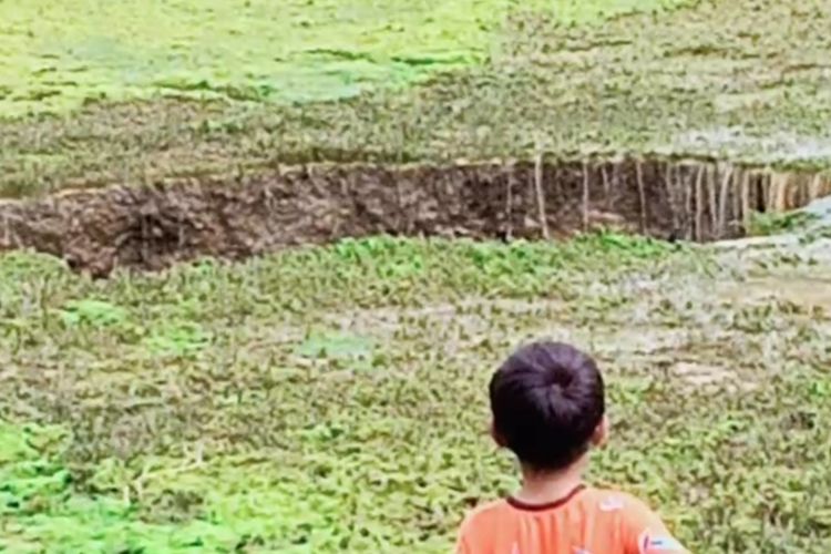 Seorang anak melihat lubang ambles di kolam Kampung Kubang, Desa Cimahpar, Kecamatan Kalibunder, Sukabumi, Jawa Barat, Minggu (27/12/2020).