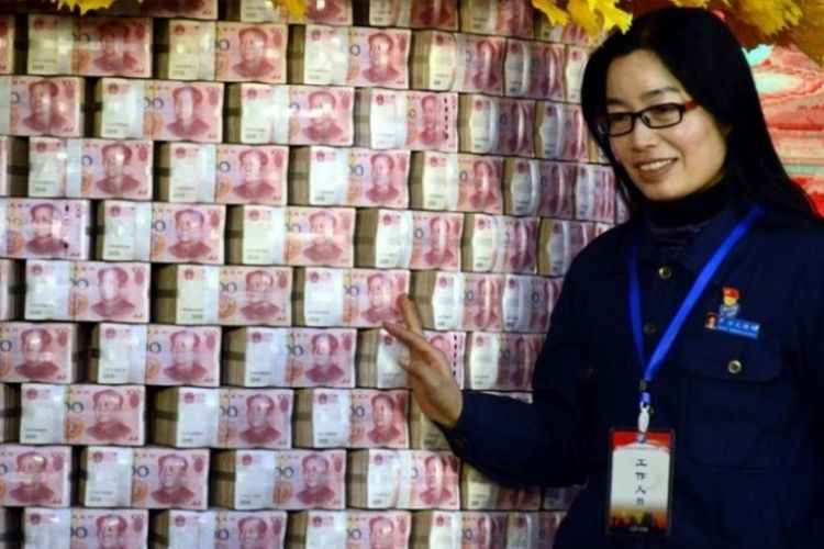Seorang staf sebuah pabrik baja di China berdiri di tumpukan uang tunai yang akan dibagikan kepada para karyawan sebagai bonus tahunan.