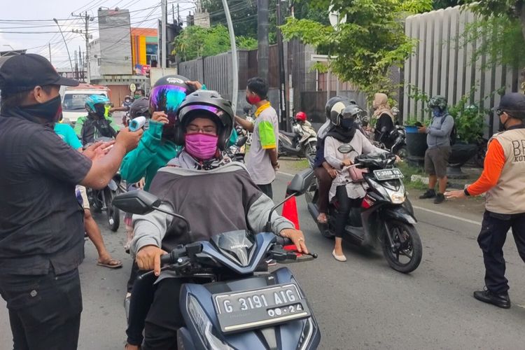 Petugas memeriksa suhu tubuh warga yang melintas di posko chek point di Jalan Jendral Sudirman Kota Tegal, Rabu (22/4/2020)