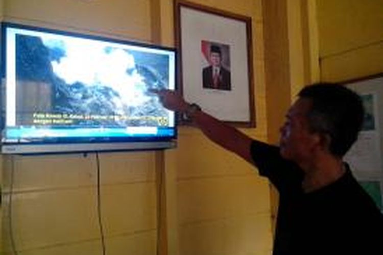 Umar Rosadi, Pengawas Gunung Api Wilayah Jawa Timur-Jawa Tengah Badan Geologi Kementerian ESDM menunjukkan foto kawah yang terbentuk akibat erupsi 13 Februari 2014, di pos pantau Kelud di Kecamatan Ngancar Kabupaten Kediri, Sabtu (1/3/2014). 