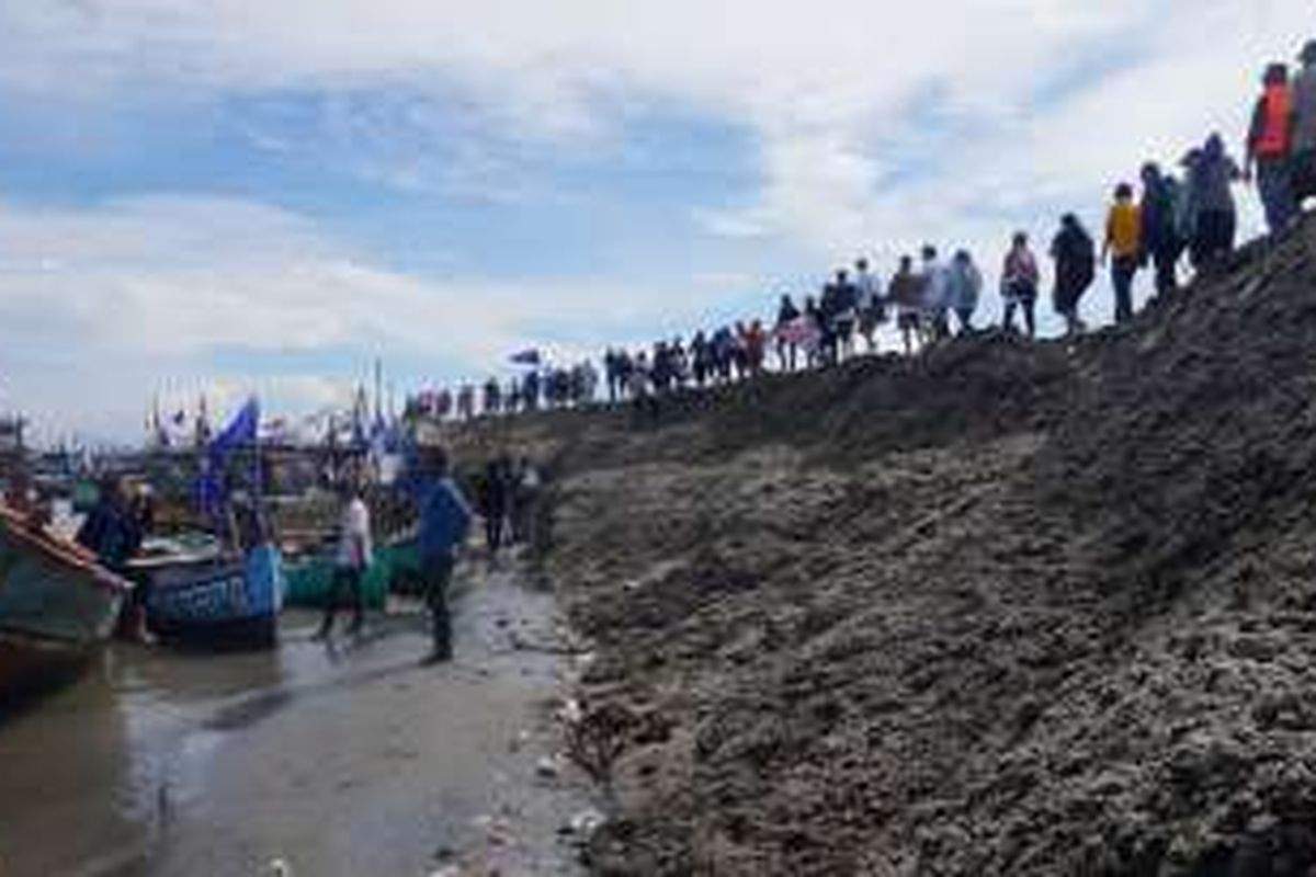 Warga berbaris di gunungan pasir Pulau G, saat melakukan aksi penyegelan pulau, Minggu (17/4/2016). Aksi yang diikuti ratusan warga pesisir Jakarta ini merupakan bentuk penolakan reklamasi Teluk Jakarta yang tengah berlangsung.