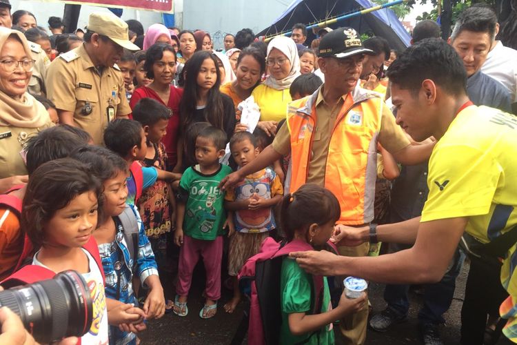 Pebulu tangkis tunggal putra dari PB Exist, Chico Aura Dwi Wardoyo (kanan) saat memberikan bantuan dan motivasi kepada anak-anak korban banjir di Kalideres, Jakarta Barat.