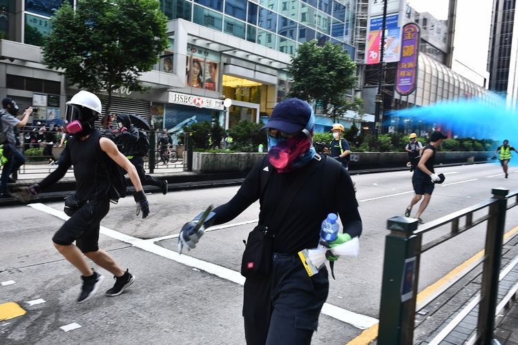 Massa demonstran berlari menghindari tembakan meriam air dalam aksi demonstrasi di Hong Kong, Minggu (20/10/2019).