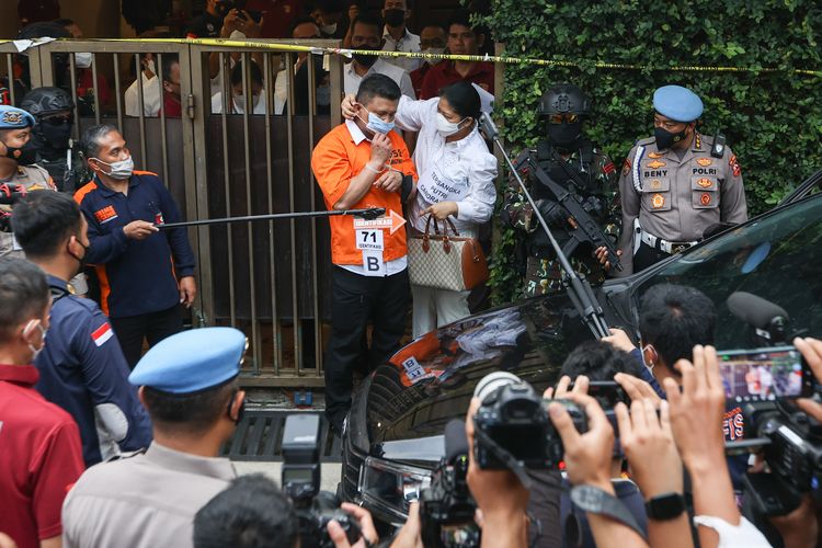 Tersangka Putri Candrawathi memasangkan masker Ferdy Sambo saat menjalani rekonstruksi kasus pembunuhan Brigadir J di rumah dinas Ferdy Sambo, Duren Tiga, Jakarta Selatan, Selasa (30/8/2022). Saat rekonstruksi penampilan Putri Candrawathi menjadi sorotan saat terlihat menenteng tas Gucci varian GG Supreme Boston Bag berwarna coklat.
