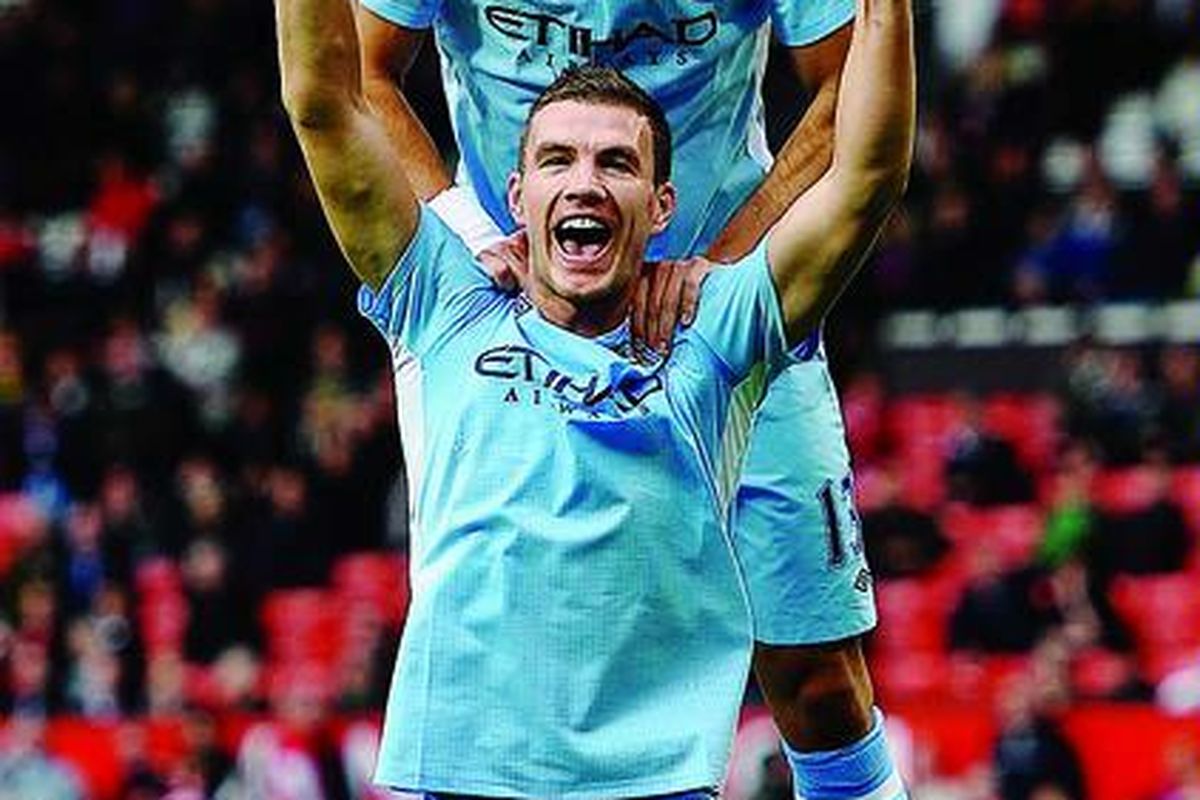Edin Dzeko dan Aleksandar Kolarov, pemain Manchester City, merayakan gol keenam timnya pada laga Liga Premier antara Manchester United melawan Manchester City di Old Trafford, Minggu (23/10), di Manchester, Inggris.