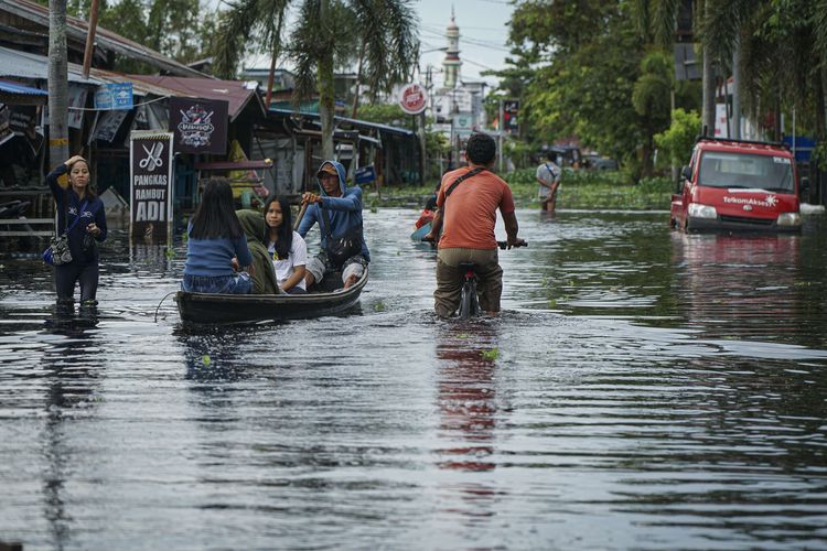 Warga berusaha menerobos jalan yang terendam banjir di Tanjung Puri, Kabupaten Sintang, Kalimantan Barat, Minggu (14/11/2021). Badan Penanggulangan Bencana Daerah (BPBD) setempat menyebutkan masih ada sebanyak 32.919 warga di tujuh kecamatan yang terdampak banjir masih berada di tempat pengungsian, meskipun ketinggian air mulai menurun.