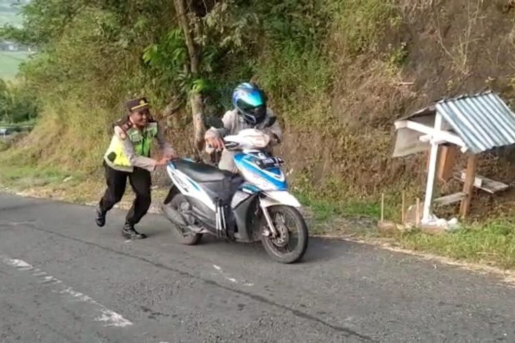 Polisi mendorong sepeda motor di tanjakan Clongop, Gunungkidul DI Yogyakarta.