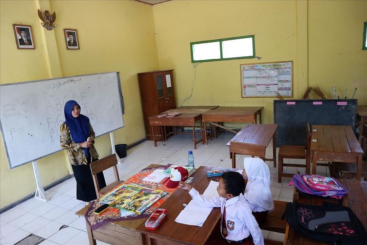 Salah satu guru SDN Sumberaji II, Sriami, membimbing 2 murid barunya, Selasa (16/7/2019). Sekolah dasar itu berada di Dusun Ngapus, Desa Sumberaji, Kecamatan Kabuh, Kabupaten Jombang, Jawa Timur.