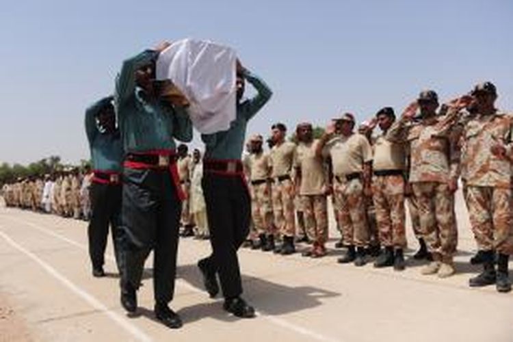 Pasukan Rangers Pakistan memberikan hormat ketika peti jenazah rekan mereka yang tewas dalam baku tembak di Bandara Internasional Karachi, Senin (9/6/2014) melintas. Kelompok Taliban menyerang bandara internasional itu pada Minggu malam dan menewaskan tak kurang dari 28 orang.