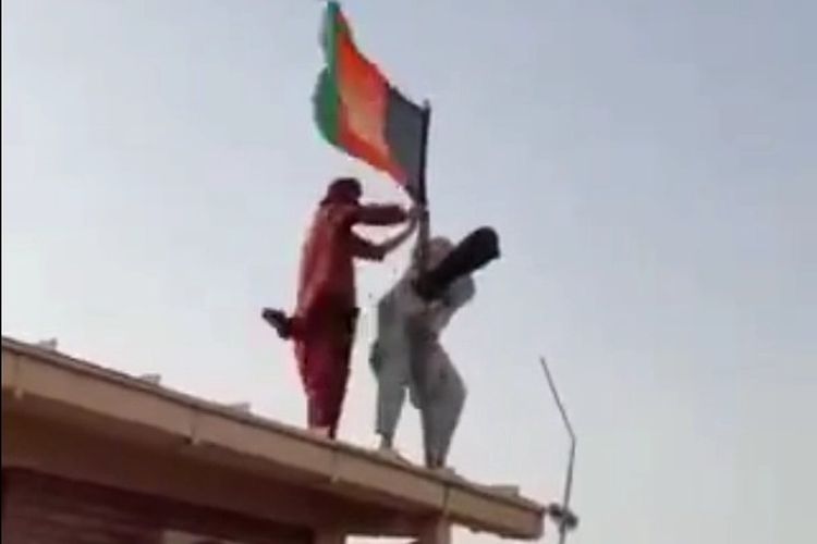 Militan Taliban yang akan merobek bendera nasional Afghanistan di pos pemeriksaan perbatasan di Islam Qala. [Via The Sun]