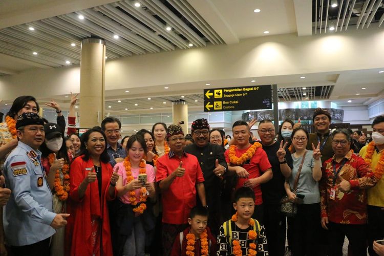 Sebanyak 210 wisatawan asal China saat foto bersama dengan Gubernur Bali I Wayan Koster dan pejabat dari instansi terkait di Terminal Kedatangan Internasional Bandara I Gusti Ngurah Rai, Badung, Bali, pada Minggu (22/1/2023). /Humas PT Angkasa Pura I Bandara Internasional I Gusti Ngurah Rai. 