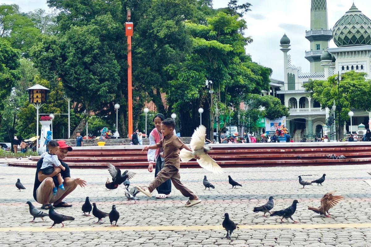 Burung merpati menjadi salah satu daya tarik  Alun-alun Kota Malang, Jawa Timur,bersama keluarga untuk menikmati libur Lebaran, Selasa (24/3/2026) pagi. 