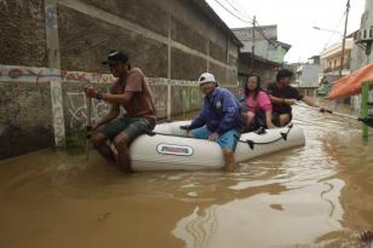 Warga diungsikan menggunakan perahu karet dari banjir yang melanda kawasan Bidara Cina, Jakarta, Senin (13/1/2014). Hujan yang melanda Jakarta sejak Minggu pagi ditambah meluapnya sungai Ciliwung akibat banjir kiriman dari Bogor mengakibatkan sejumlah kawasan ini terendam banjir. KOMPAS IMAGES/RODERICK ADRIAN MOZES