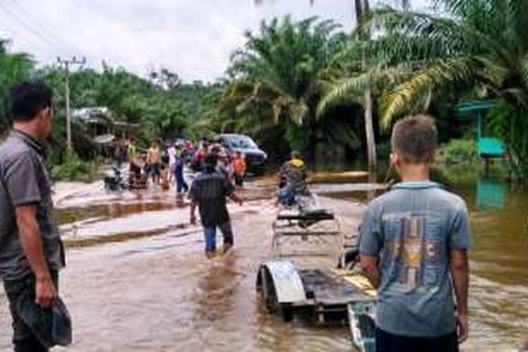 Warga melintas di lokasi banjir di Desa Cingkam, Kecamatan Gunung Meriah, Aceh Singkil, Jumat (6/1/2017)