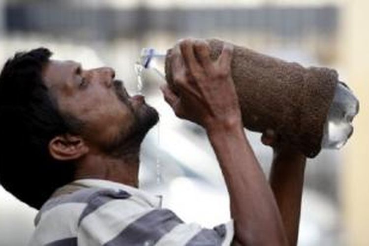 Seorang pria minum air dari botol di tengah hari yang terik di Allahabad, India, Minggu  (31/5/2015). 