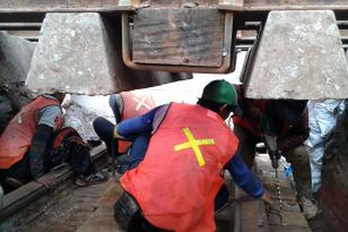 Pekerja harian lepas (PHL) PT Kereta Api Properti Manajemen (KAPM) yang harus bekerja di bawah rel Stasiun Manggarai, Jakarta Selatan, Rabu (4/2/2015). Rel tersebut masih digunakan oleh kereta api untuk lewat sehingga setiap ada kereta datang, para PHL bersembunyi di bawah rel tersebut.
