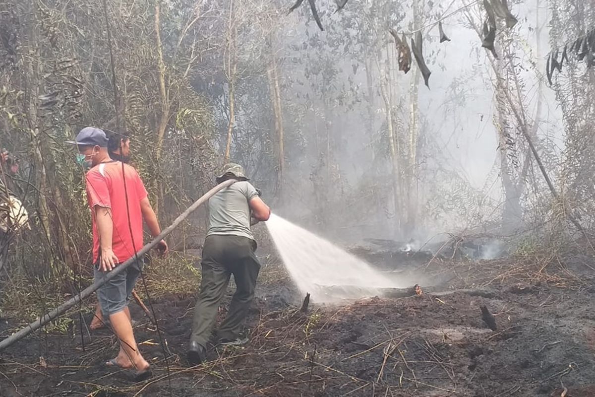 Petugas gabungan berupaya memadamkan karhutla mendekati rumah warga di Desa Rimbo Panjang, Kecamatan Tambang,  Kabupaten Kampar, Riau, Selasa (17/9/2019).