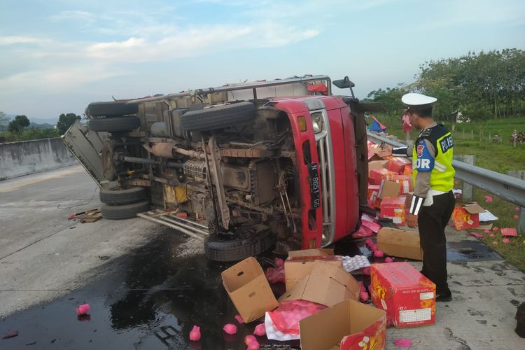 TERGULING—Truk bermuatan buah apel terguling setelah ditabrak dari belakang truk mengangkut roti di ruas tol Surabaya-Madiun kilometer 620.200 lajur B di wilayah Kecamatan Saradan, Kabupaten Madiun, Jawa Timur, Senin (23/5/2022) sore. Akibat kecelakaan itu satu penumpang truk bermuatan roti meninggal dunia.