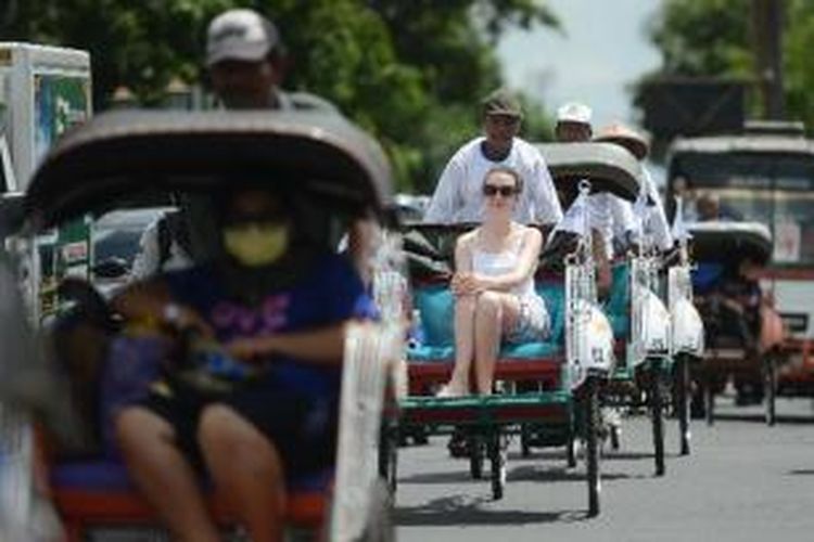 Wisatawan asing asal Belgia menaiki becak untuk menikmati suasana kota di kawasan Titik Nol, Yogyakarta, Selasa (2/4/2013). Berwisata dengan becak merupakan salah satu paket wisata yang banyak diminati wisatawan asing saat berkunjung di Yogyakarta.