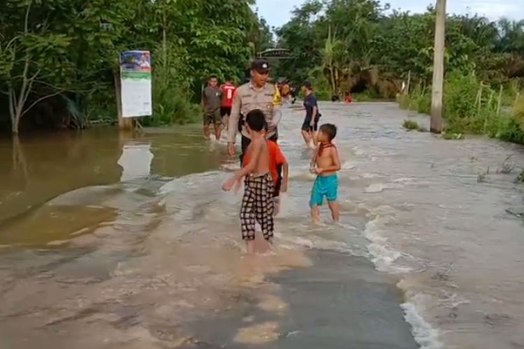 Petugas kepolisian memantau warga yang berwisata di lokasi banjir di Kecamatan Rengat Barat, Kabupaten Indragiri Hulu, Riau, Minggu (24/12/2023).