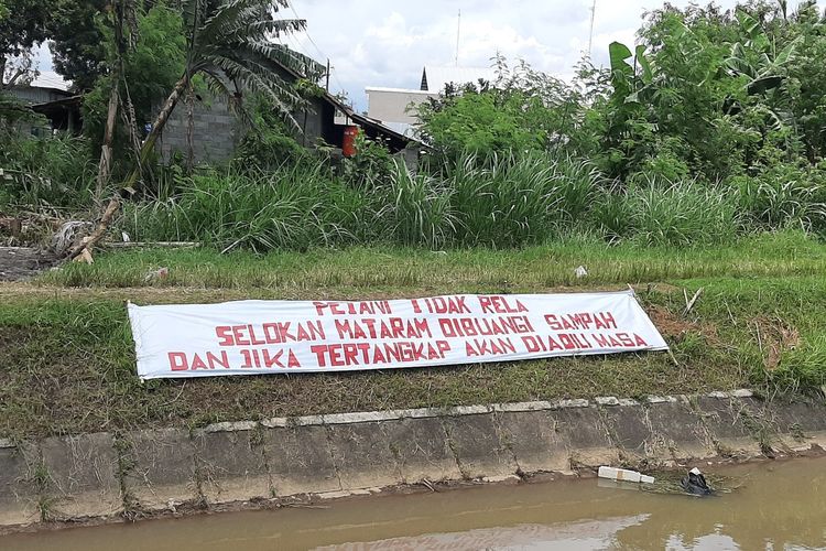 Para petani memasang spanduk himbuan agara tidak membuang sampah di Selokan Mataram.