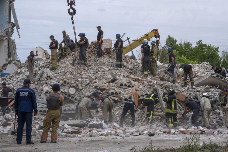 Petugas penyelamat menyaring puing-puing di lokasi kejadian setelah roket Rusia menabrak blok perumahan apartemen, di Chasiv Yar, wilayah Donetsk, Ukraina timur, Minggu, 10 Juli 2022.