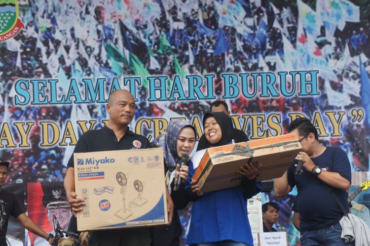 Bupati Karawang Cellica Nurrachadiana (tengah) membagikan hadiah kepada buruh yang lahir 1 Mei pada peringatan May Day di Disnakertrans Karawang, Rabu (1/5/2019).


