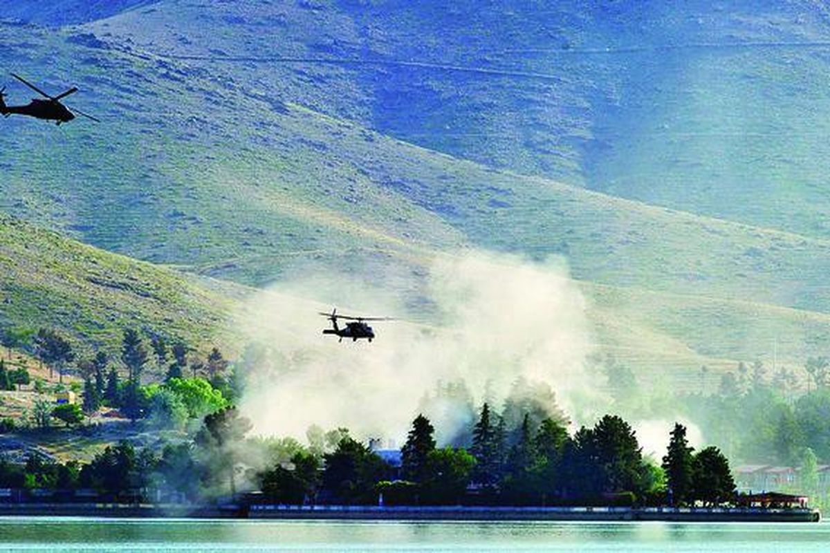 Helikopter UH-60 Black Hawk milik NATO terbang mengitari Hotel Spozhmai di tepi Danau Qargha, luar kota Kabul, Jumat (22/6). Kelompok militan Taliban bersenjatakan senapan dan senjata pelontar roket menyerang hotel tersebut pada malam sebelumnya, menyebabkan sedikitnya 18 orang tewas dan puluhan orang disandera, termasuk perempuan dan anak-anak. 