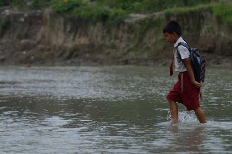 Siswa menyeberangi sungai untuk kembali ke rumah setelah masuk sekolah pada hari pertama di Desa Jragung, Kecamatan Karangawen, Kabupaten Demak, Jawa Tengah, Senin (15/7/2013)