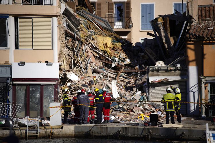 Petugas pemadam kebakaran dan petugas penyelamat berdiri di sebuah gedung tempat tinggal tiga lantai setelah runtuh diduga akibat ledakan gas di kota pantai Mediterania Sanary-sur-Mer, Perancis, Selasa (7/11/20210). (AP Photo/Daniel Cole)