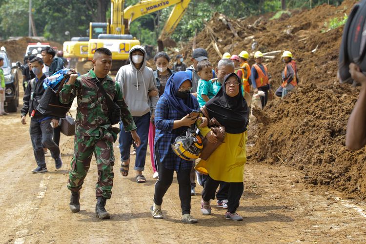 Anggota TNI membantu warga melewati lokasi  tanah longsor di Kampung Pos, Desa Cijedil, Kecamatan Cugenang, Kabupaten Cianjur, Jawa Barat, Selasa (22/11/2022). Sedikitnya 162 orang meninggal dunia, 326 warga luka-luka, dan 13.784 orang mengungsi akibat gempa bermagnitudo 5,6 di Cianjur.