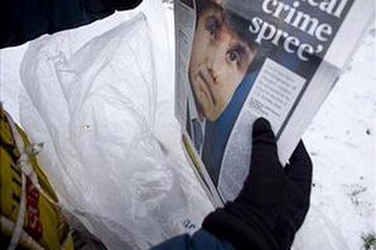 Seorang loper memegang koran dengan halaman muka memuat foto berikut kasus  Rod Blagojevich di luar gedung James R. Thompson yang menjadi lokasi kantor gubernur Illinois itu di Chicago, 10 Desember 2008. 