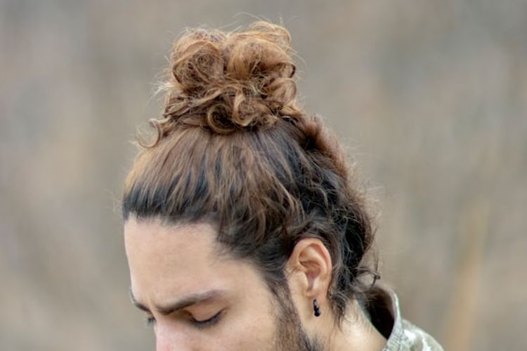 Model rambut man bun dengan cepol di bagian atas kepala.