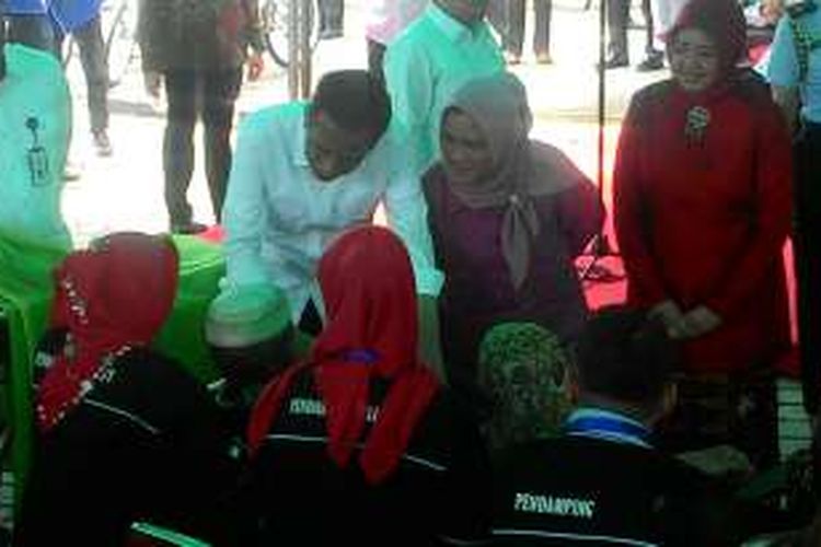 Presiden Joko Widodo mencondongkan badan, menyendengkan telinga, lalu mengangguk-angguk saat bercakap-cakap dengan warga di Embarkasi Haji Kelurahan Manggar Baru, Balikpapan, Kalimantan Timur, Kamis (24/3/2016) siang.