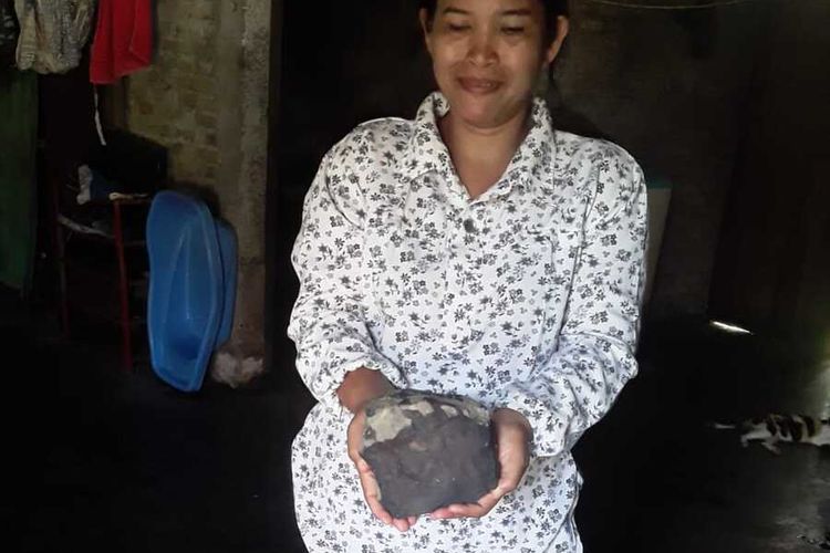 Isteri Josua Hutagalung, menunjukkan bongkahan batu yang diduganya benda langit (meteor) yang jatuh menimpa kediamannya di Dusun Sitahan Barat, Desa Satahi Nauli, Kecamatan Kolang, Kabupaten Tapanuli Tengah, Sabtu (1/8/2020).
