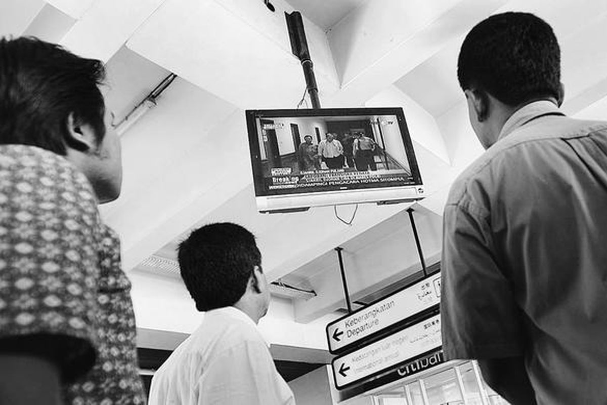 Warga melihat liputan seputar kepulangan Sjahril Djohan ke Indonesia yang disiarkan langsung oleh salah satu stasiun televisi swasta di Bandara Soekarno-Hatta, Tangerang, Banten, Selasa (13/4).