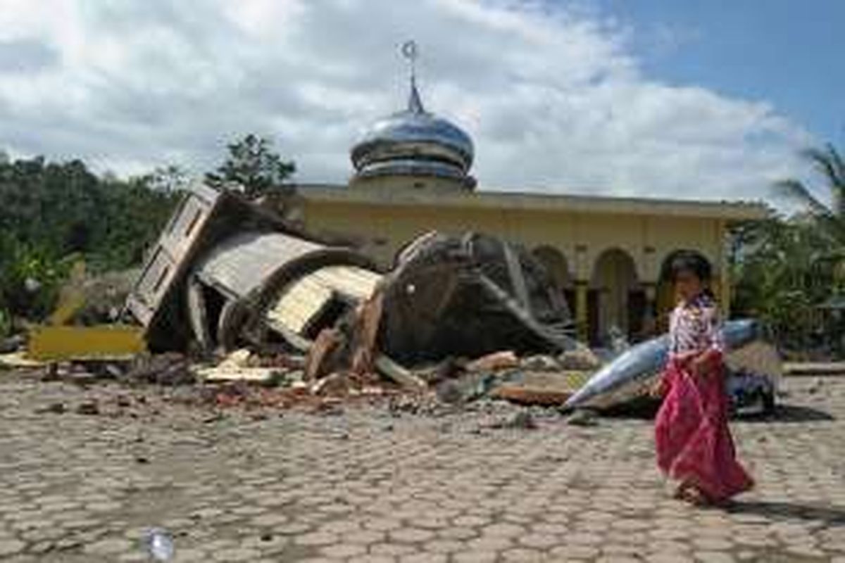 Seorang anak melewati mesjid yang rusak akibat gempa bumi berkekuatan 6,4 skala richter, di Pidie, Aceh, Rabu (7/12/2016). Puluhan orang tewas dalam peristiwa yang terjadi pukul 05.03 WIB ini.