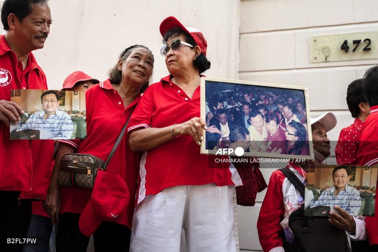 Para pendukung mantan perdana menteri Thailand, Thaksin Shinawatra, memegang fotonya sambil menunggu di luar kediamannya di Bangkok pada 11 Mei 2026.