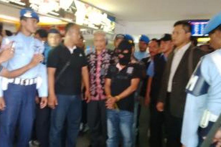 M saat tiba di Bandara Husein Sastranegara, Bandung, Jawa Barat, Selasa (24/2/2015) sekitar pukul 17.30 WIB dikawal BNN Provinsi Jabar dan personel TNI AU Lanud Husein Sastranegara. M merupakan tersangka yang menyelundupkan 800 gram sabu ke Bandung melalui jasa TKI pada 15 Januari 2015.