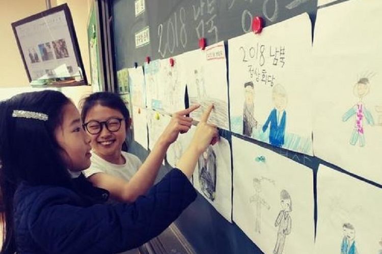 Dua murid sebuah sekolah di Gwangju, Korea Selatan, memperhatikan gambar tentang KTT Antar-Korea (27/4/2018). Dinas pendidikan kota tersebut mengajukan permintaan karyawisata sekolah ke Korut.