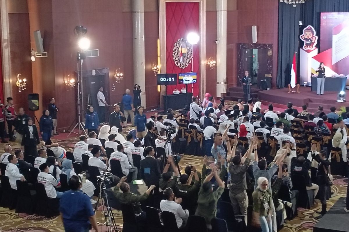 Salah seorang panitia penyelenggara membawa papan bertuliskan 'Harap Tenang' guna menenangkan para pendukung ketiga paslon Bupati Kabupaten Cianjur, di Hotel Sutan Raja, Soreang, Kabupaten Bandung, Jawa Barat, Jumat (25/10/2024)