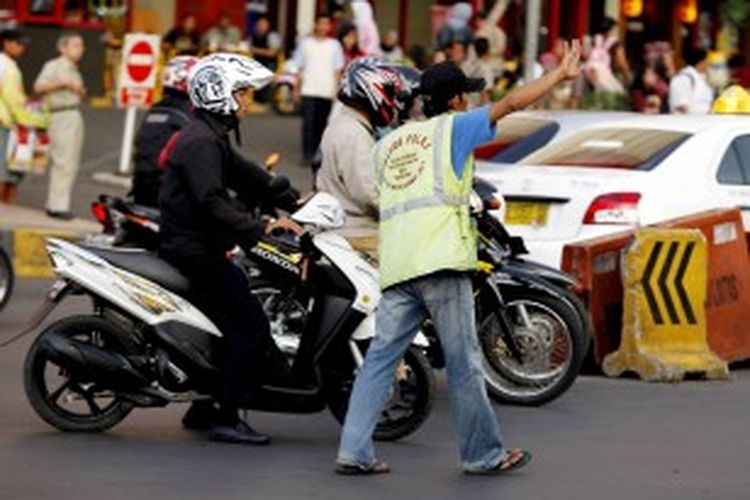 Warga atau kerap disebut dengan polisi cepek mengatur lalu lintas kendaraan di dekat pusat perbelajaan Cililitan, Jakarta Timur, Selasa (2/11/2010). Meski tidak meminta namun kebanyakan pengguna kendaraan roda empat kerap memberinya uang receh. 