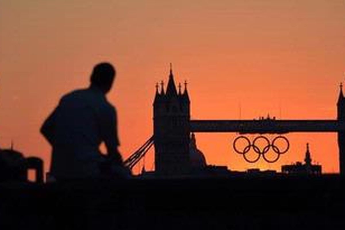 Dua orang menikmati sunset di belakang Tower Bridge di Sungai Thames di kota London, lima hari sebelum dimulainya Olimpiade London.
