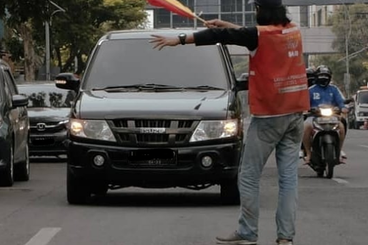 Ilustrasi juru parkir yang menggunakan bendera tangan sebagai alat bantu isyarat pemberi arahan parkir.