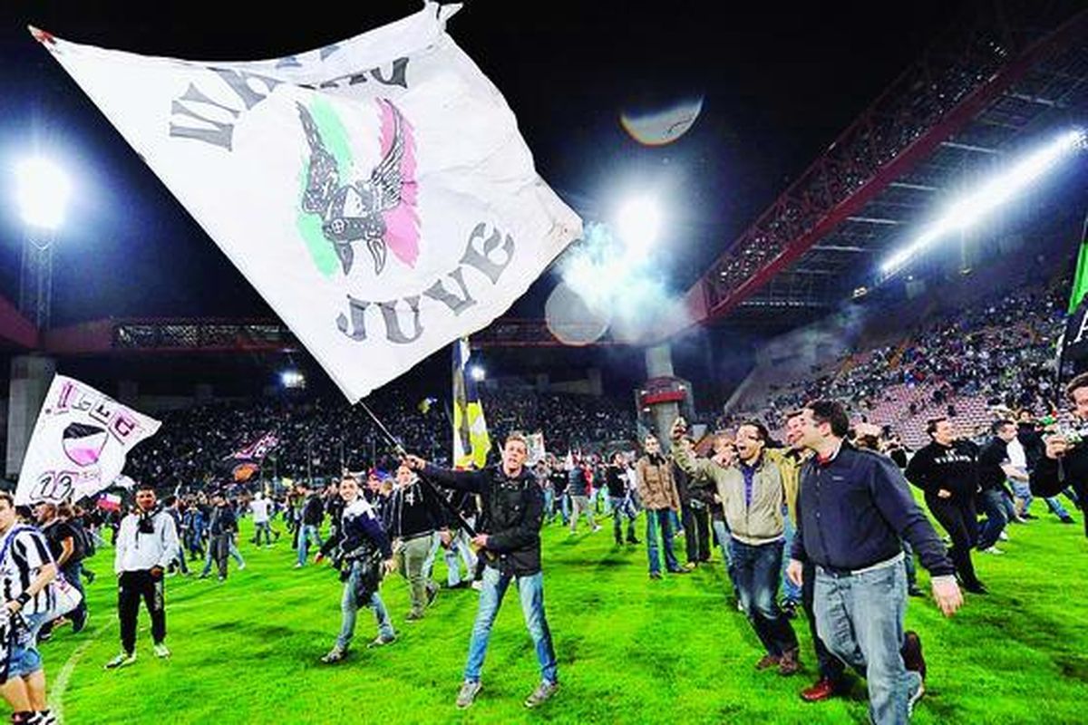 Seorang pendukung melambai-lambaikan bendera Juventus untuk merayakan gelar juara  Liga Italia setelah klub itu mengalahkan Cagliari di Stadion Nereo Rocco di Trieste. Juve memastikan gelar setelah AC Milan menyerah 2-4 dari Inter Milan.