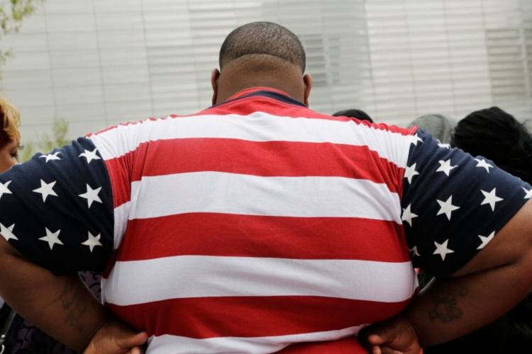 Seorang pria dengan kelebihan berat badan mengenakan baju dengan pola bendera AS ketika berkunjung ke World Trade Center, New York, AS pada 8 Mei 2014. Hampir 42 persen orang dewasa di AS mengalami obesitas. 