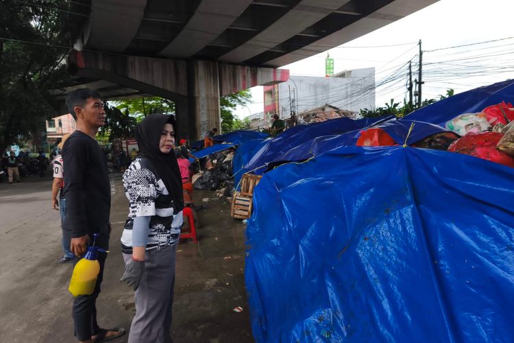 Lurah Cipayung, Dini Nurlianti saat kerja bakti untuk menutup tumpukan sampah di Kolong Flyover Ciputat, Tangerang Selatan, Minggu (14/12/2025).
